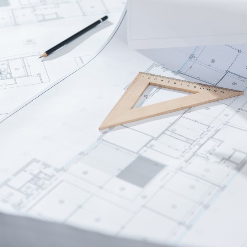 close-up shot of architecture plans and drawing supplies on table